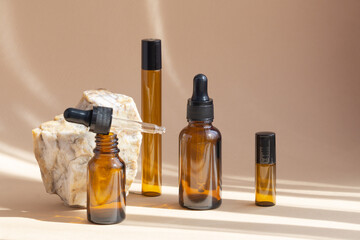 Mock-up of amber-colored glass bottles with dropper lid on beige background. Containers with facial serum, retinol close-up