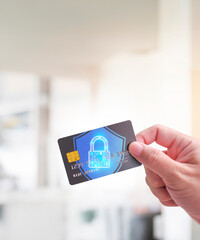 Close up of man hand holding credit or debit card with padlock, protection of financial...