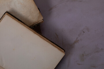 Closeup top view of open vintage antique books on top each other with light purple background and copy space
