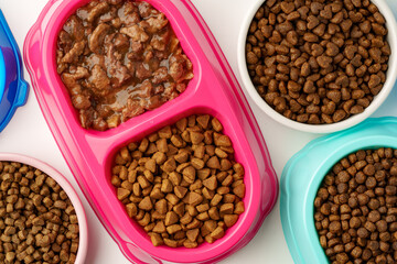 Plastic pet bowls with food isolated on white background