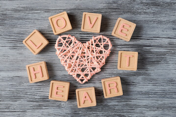 Words LOVE HEARTS spelled out with wooden blocks and adorned withcraft heart on textured wooden background