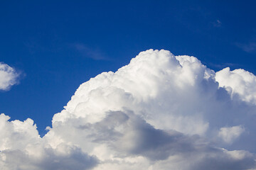 Naklejka na ściany i meble Huge fluffy cumulus cloud on blue sky. Formation before thunderstorm. Copy space