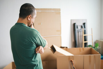 Man standing by cardboard boxes at home, preparation for moving out.