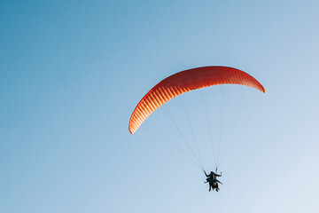 Paraglider flying over the blue sky. Concept of extreme sport, taking adventure challenge.