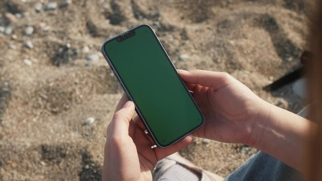 Green Screen chroma key Handheld Smartphone. Travel with phone concept, application mock up. Sunset on a tropical beach.