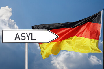 Schild mit der Aufschrift Asyl zeigt in Richtung Deutschlandflagge (Symbolbild, Composing)