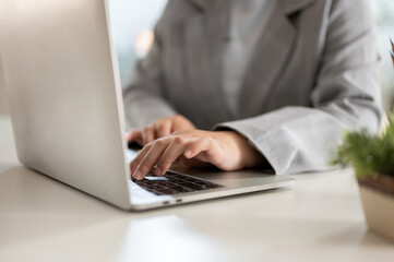 Close-up image of a businesswoman working on her laptop computer at her desk in the office.