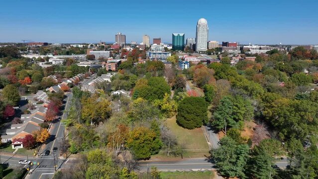 Winston-Salem skyline with autumn trees in foreground. Aerial truck shot on fall day in North Carolina city.