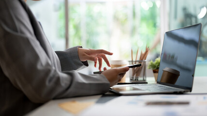 Cropped image of a professional businesswoman using her smartphone at her office desk.