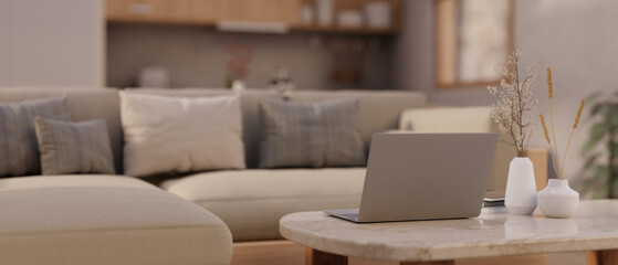 A laptop computer on a marble coffee table in a modern spacious living room. Home workspace