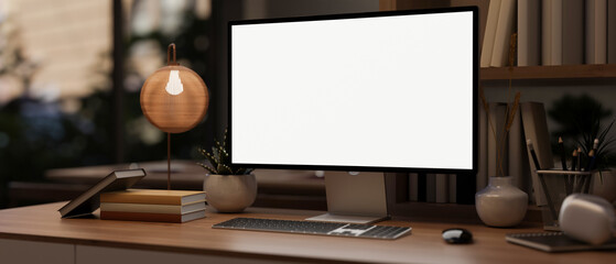 A modern office in the evening with a white-screen PC computer mockup on a wooden desk.