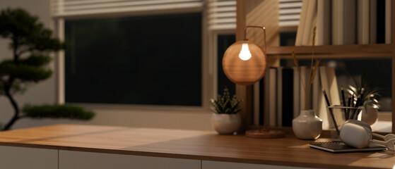A copy space and accessories on a wooden table in a modern, cosy working room at night.