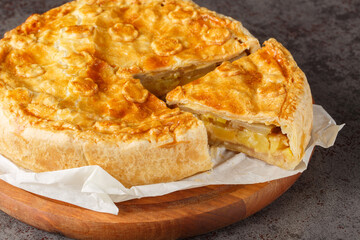 Fruit and vegetable Swiss cholera pie with apple, potato, pear, onion and cheese close-up on a wooden board on the table. Horizontal