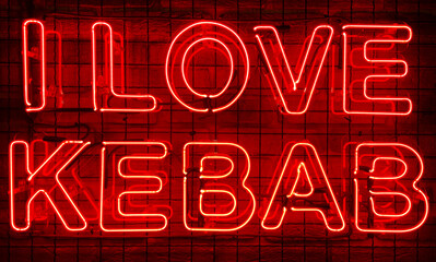 Neon shining sign in red color on a brick wall in the dark with the inscription or slogan I love...