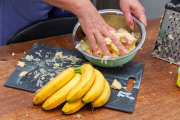 Hands preparing banana pie in the kitchen.