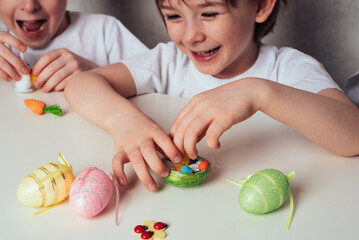 Close-up of smiling child girl's hands playing with decorative Easter eggs, chicks and nest....