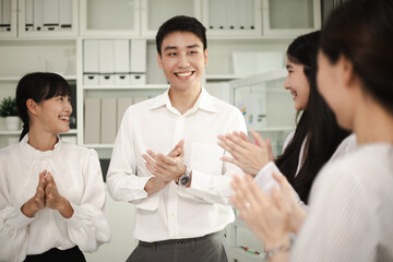 Happy group of businesspeople clapping in office. Handsome young business man standing confident in...