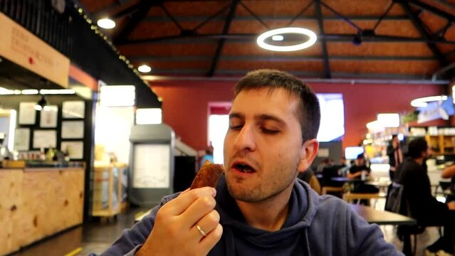 Man eating delicious cod croquette in Beira Mar Market, Porto. Slow motion