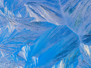 Beautiful ice pattern and sunlight close up on window glass early in the morning, natural winter background  