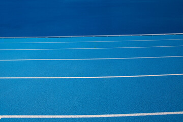 Fototapeta na wymiar Blue Olympic track lanes with white stripes, an empty background suitable for copy space, represent the concept of physical sports and running, symbolizing commitment and pathways towards goals