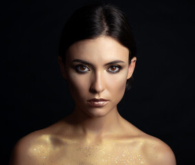 Close-up portrait of young woman with golden makeup.