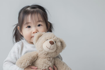 A little girl hugging teddy bear on white studio background. Children's day concept. Copy space