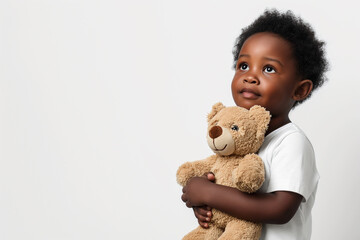 A little black boy hugging teddy bear on white studio background. Children's day concept. Copy space