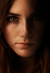 Fototapeta premium Woman, beauty and portrait with shadow and freckles in studio in the dark. Natural, makeup and female person face from Ireland with cosmetics treatment, confidence and serious with black background