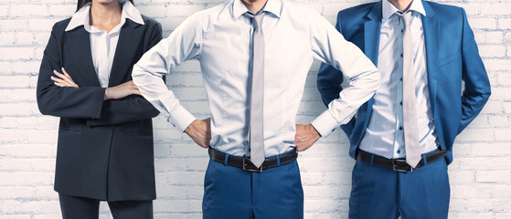 Wide image of headless businesspeople on concrete wall background. Teamwork concept.