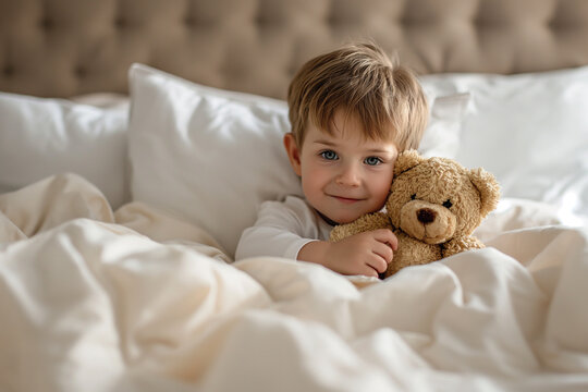 A little cute boy hugging teddy bear on bed. Children's day concept.