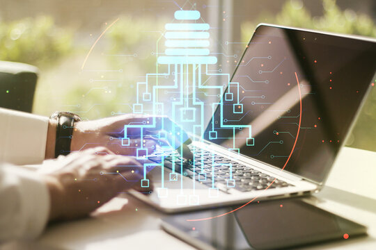 Double exposure of creative light bulb hologram with chip and hands typing on laptop on background, idea and brainstorming concept