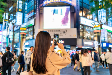 Naklejka premium Young female tourist taking a photo of the Ximending shopping street landmark and popular attractions in Taipei, Taiwan
