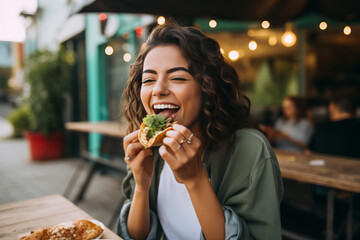 Young woman eating taco on a food court - obrazy, fototapety, plakaty