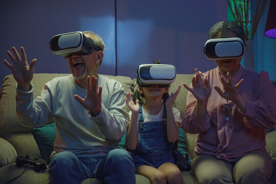 Asian elderly with child play VR video game, family entertainment, granddaughter and grandparents playing together exciting interesting video games using virtual reality headsets living room at home - Powered by Adobe