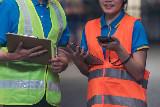 Warehouse management team check stock inventory. Asian men women worker use bar code scaner scan goods shelf writing checklist on clipboard. Teamwork logistics staff counting products store inventory