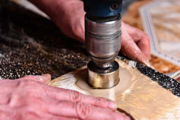 Drilling hole in ceramic tile with diamond crown using template and water.