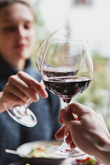 Close up of hands young man and woman clinking with glasses of red wine at restaurant
