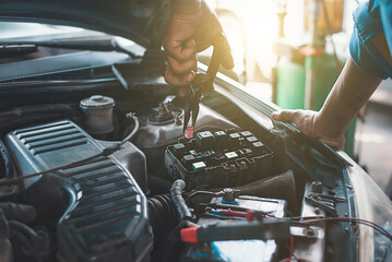 A mechanic uses a fuse clip tool to replace the spare fuse in the car's fuse box.