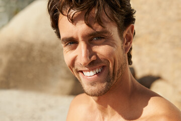 Man, smile and portrait at the beach on a holiday and summer vacation outdoor with travel. Happy,...