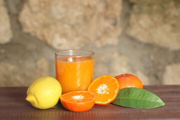 tangerine juice in a glass and tangerines on wood 
