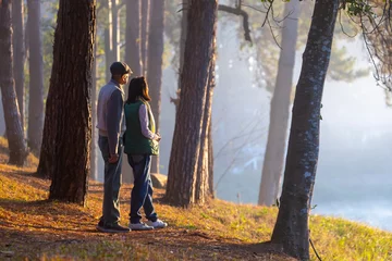 Fotobehang Back view of senior couple watching sunrise together in the pine forest after hiking for love, marriage and healthy long last relationship bonding and longevity concept © Akarawut