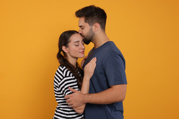 Naklejka premium Man kissing his girlfriend on orange background