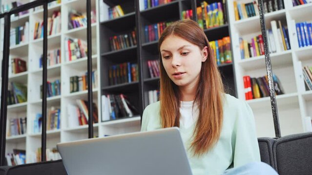 Young woman articulates point during video call, expression active and explanatory against backdrop of bookshelves. Interactive online learning concept