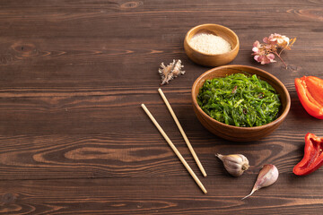 Chuka seaweed salad in wooden bowl on brown wooden. Side view, copy space.