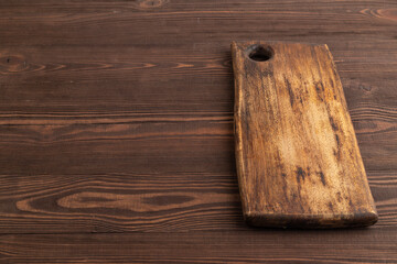 Naklejka na ściany i meble Empty rectangular wooden cutting board on brown wooden. Side view, copy space