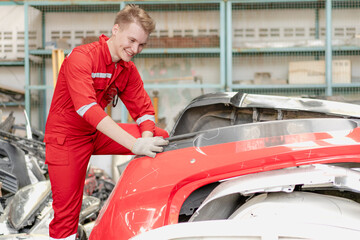 Auto mechanic repairman working on transport body bumper assembly on damaged car at motor repair service station. Technician fixing engine problem vehicle from collision crash accident automotive
