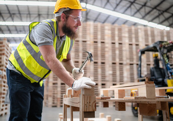 Confident production worker busy working at lumber warehouse of wooden furniture factory. Skilled technician wears safety hardhat standing in hardwood plank manufacturing facility using serious tool.