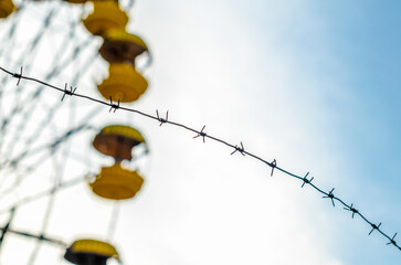background barbed wire and cabins carousel wheel in an abandoned amusement park in Chernobyl