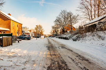 Winter cityscape, snow covered sidewalk and melting snow street with frozen dirty snow, rock salt...