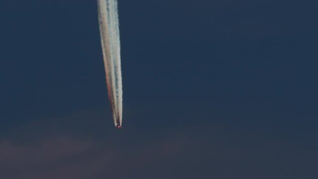 Telephoto shot of an airplane with vivid contrail in blue sky